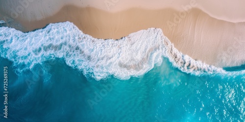 Sandy beach aerial view  with soft beige sand and waves of blue