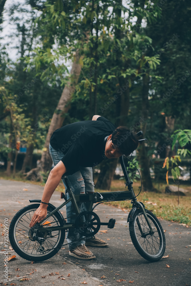 Young handsome bearded man taking a break while travelling the city with his bicycle using his digital tablet looking away thoughtfully