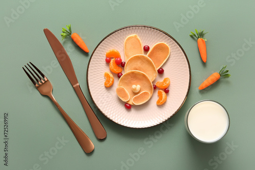 Funny Easter bunny pancakes with mandarin and berries on green background photo