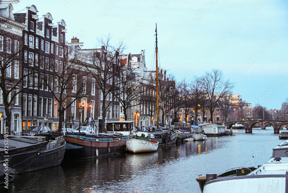 The scenic view of the buildings and canal in the city of Amsterdam in Netherlands in the twilight