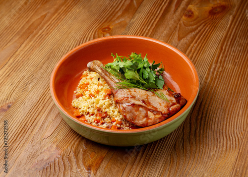 Fototapeta Naklejka Na Ścianę i Meble -  Duck leg with couscous in a plate on a wooden background