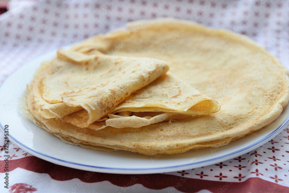  traditional french pancake homemade- folded crepe in a plate on a red and white tablecloth
