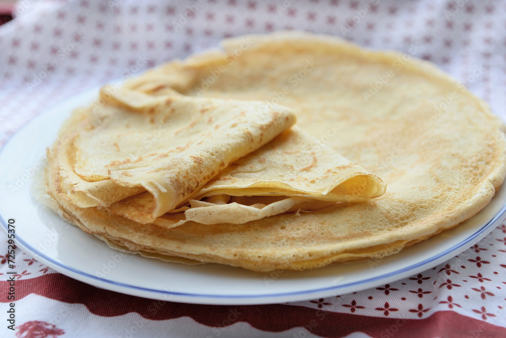 traditional french pancake homemade- folded crepe in a plate on a red and white tablecloth traditional french pancake homemade- folded crepe in a plate on a red and white tablecloth