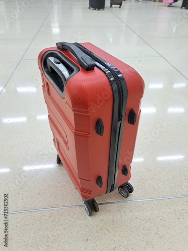 A red suitcase with black lines on the zipper and wheels is very suitable for long trips or travel photo