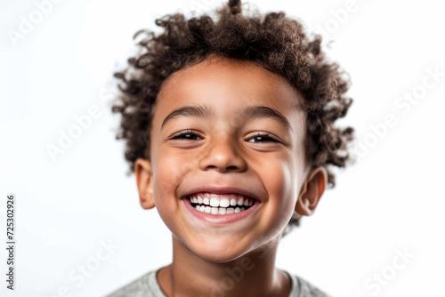 Joyful young boy with curly hair smiling brightly on white background. Child happiness and innocence.
