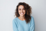 Joyful woman with curly hair wearing light blue sweater. Positive emotions and confidence.