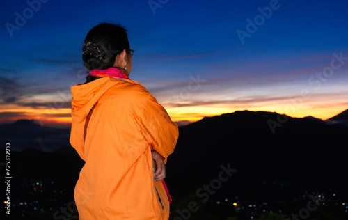 Rear view: A woman waits for the sun to rise up from behind Mount Sindoro photo
