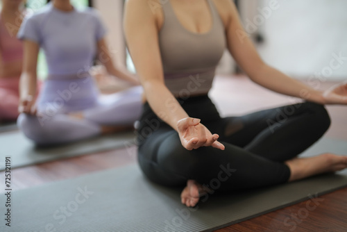 Groups of Asian women practicing basic position relaxing meditation on the mat floor at yoga class fitness gym. Young Asian women practice relaxing meditation lotus pose on a yoga mat in a fitness.