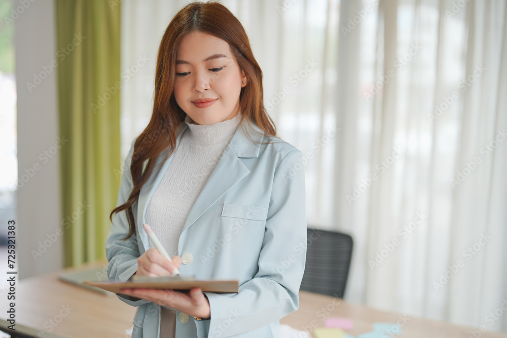 Aaian businesswoman worker holding a notebook, she is working in office. Aaian businesswoman worker holding a notebook, she is working in office.