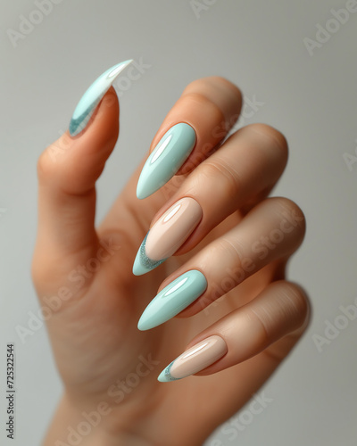 Female hand with long nails and light blue manicure with bottles of nail polish