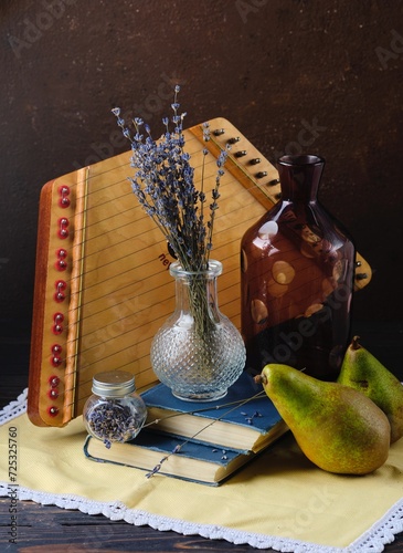 Still life with a bouquet of dried lavender in a transparent vase, dulcimer, books and two pears. Interior paintings, design. photo