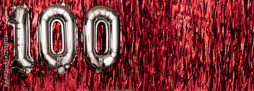 Silver foil balloon number, digit one hundred on red background. Birthday greeting card with inscription 100. Anniversary celebration. Banner.