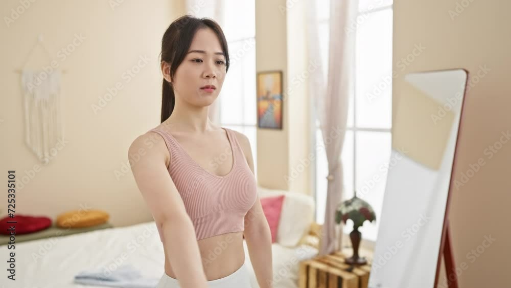 A focused asian woman exercises with dumbbells in a cozy bedroom interior, exemplifying fitness at home. A focused asian woman exercises with dumbbells in a cozy bedroom interior, exemplifying fitness at home.