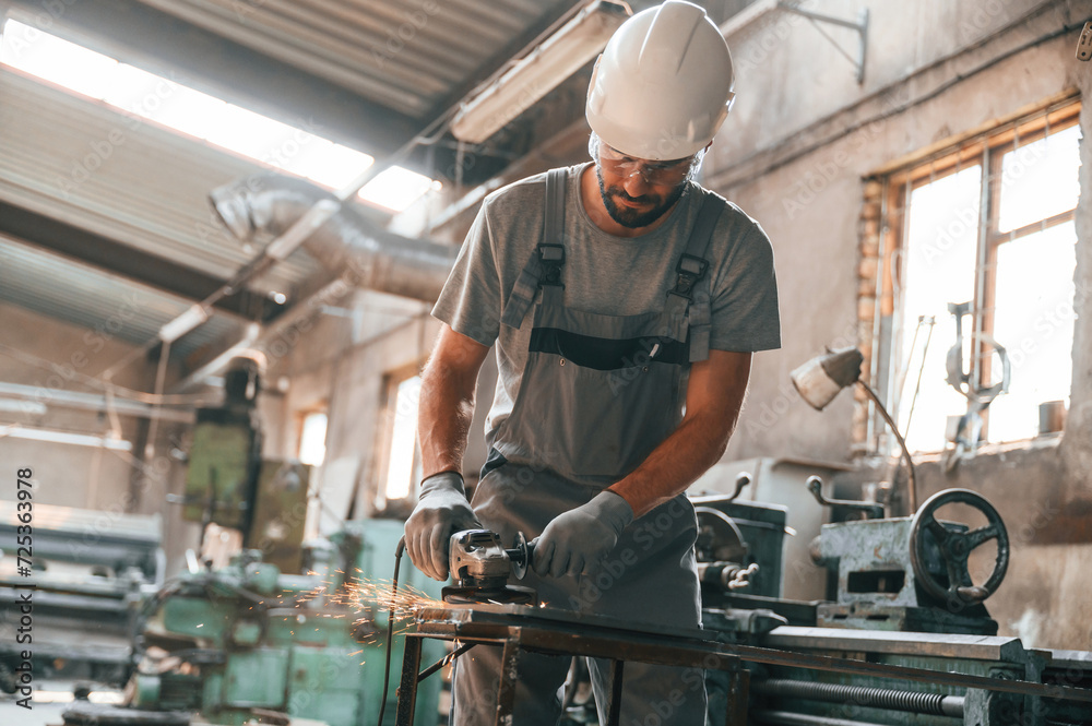 Busy day. Young factory worker in grey uniform Busy day. Young factory worker in grey uniform