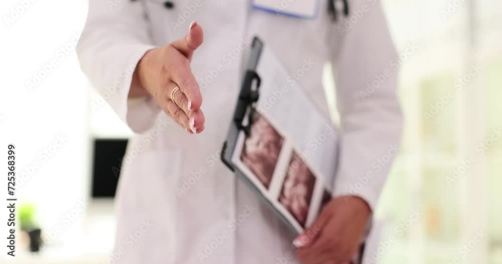 Gynecologist extends hand for handshake and holds ultrasound pictures Gynecologist extends hand for handshake and holds ultrasound pictures