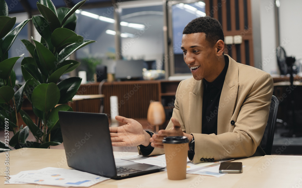 Fototapeta premium Young man using laptop and smiling at office.