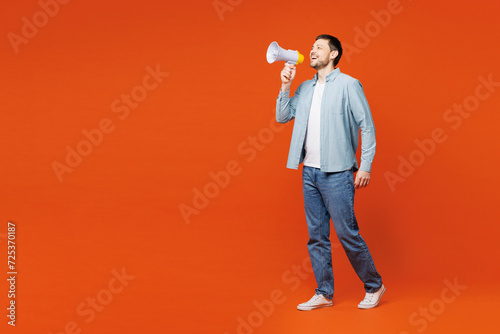 Full body young man he wears blue shirt white t-shirt casual clothes hold in hand megaphone scream announces discounts sale Hurry up isolated on plain red orange background studio. Lifestyle concept.