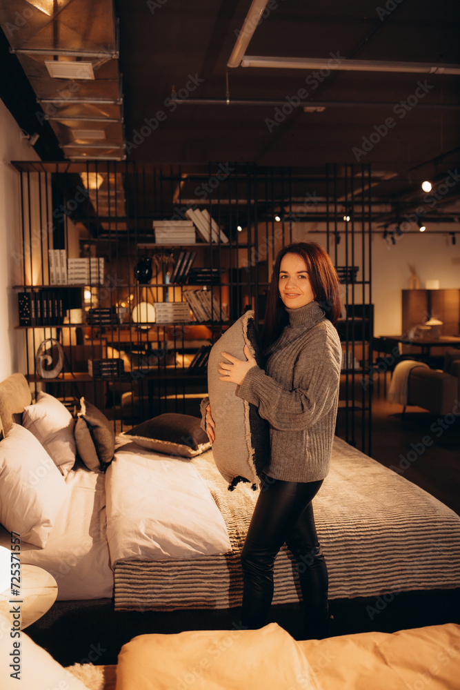 Pretty, young woman choosing the right pillow for her bed in a modern home furnishings store