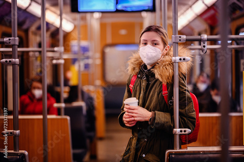 Masked Woman with Coffee in Train. Young woman with mask holding coffee cup in train