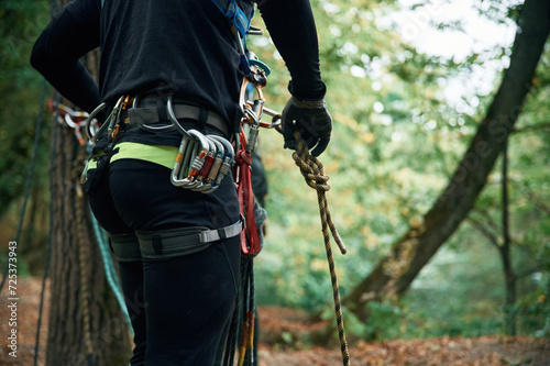 Close up particle view. Man is doing climbing in the forest by use of safety equipment