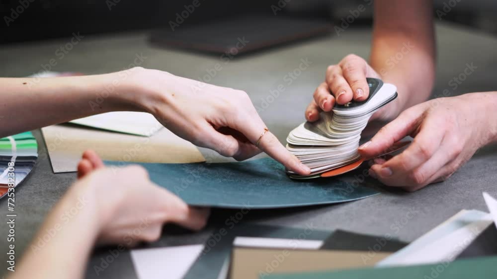 Close up hand choosing color from color sample swatch. The designer works with the customer and recommends the colors of decorative coatings.