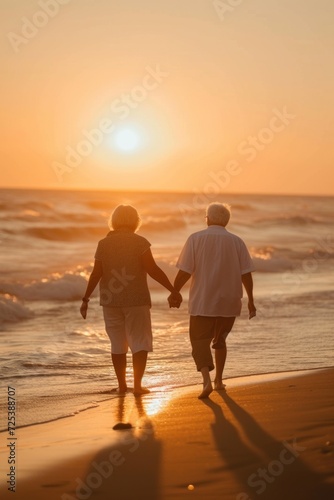 Senior couple holding hands, walking on the beach at sunset