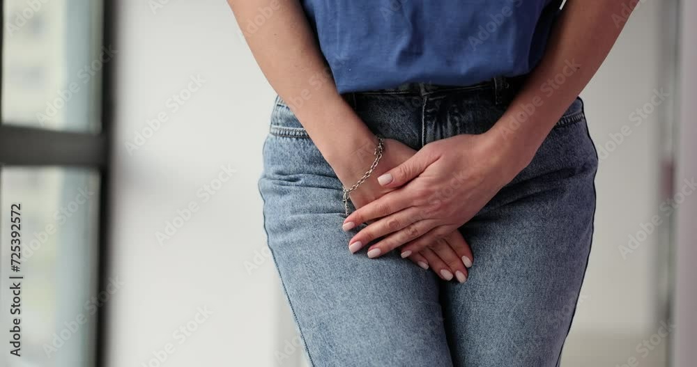 Vaginal urinary incontinence and pain of young woman holding hand to perineum