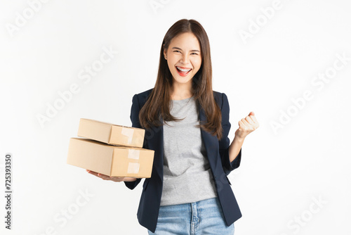 Smiling beautiful Asian businesswoman holding cardboard boxes and and fists clenched on white background. Concept delivery online.