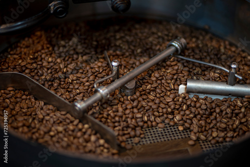 Close up of Coffee beans during the roasting process, moving paddle of the screening hopper cooling the coffee beans after roasting. Drum type roaster