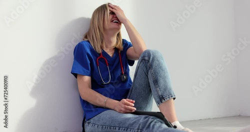 Tired surgeon sits on floor in clinic lobby laughing hysterically