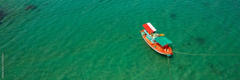 Aerial view of a traditional wooden boat floating on clear turquoise waters, symbolizing travel or fishing concepts