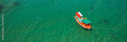 Aerial view of a traditional wooden boat floating on clear turquoise waters, symbolizing travel or fishing concepts