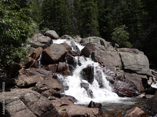 Waterfall cascading over a rocky cliff in front of lush forest in Granby. photo