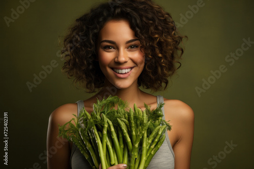 A happy and amazed woman holds a bouquet of green fennel and asparagus, promoting organic and healthy nutrition.