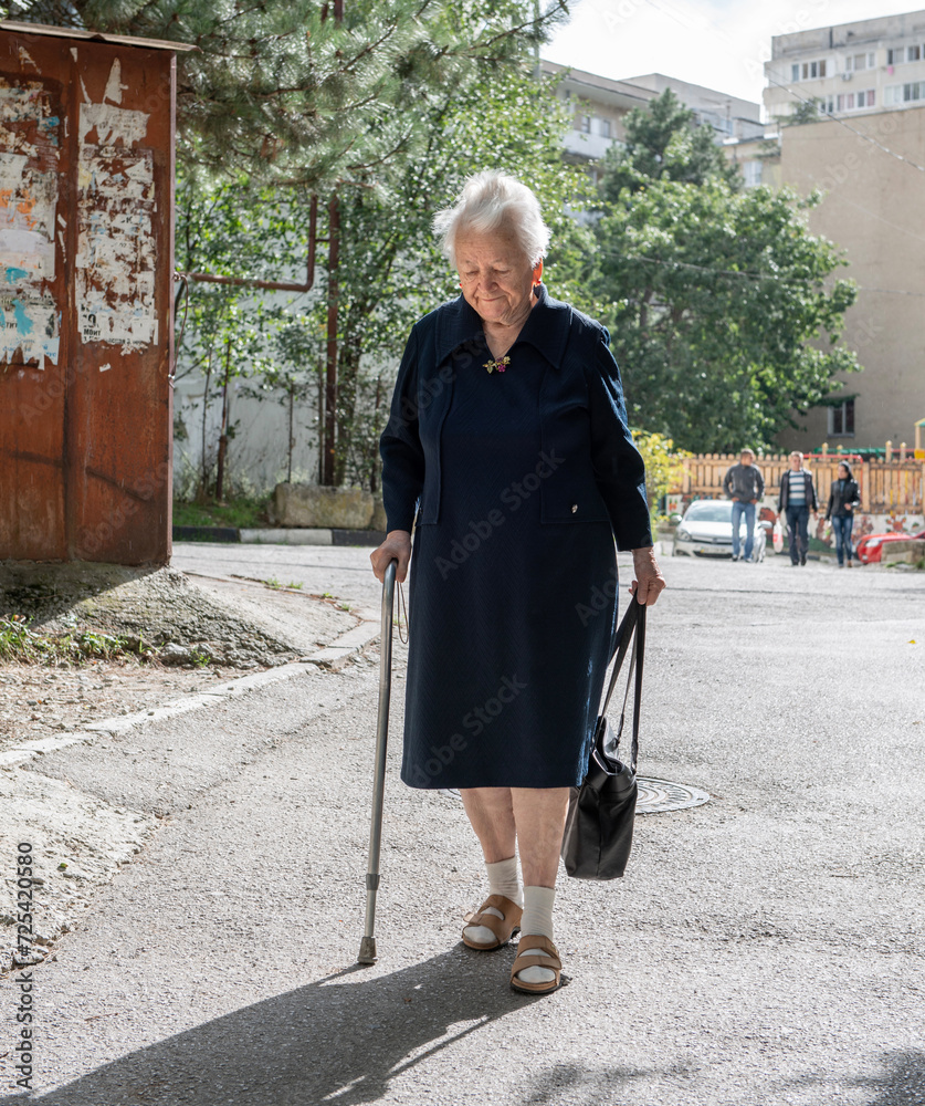 Yalta, Crimea - September 22, 2013: Old woman with a cane walking down street in sunny day
