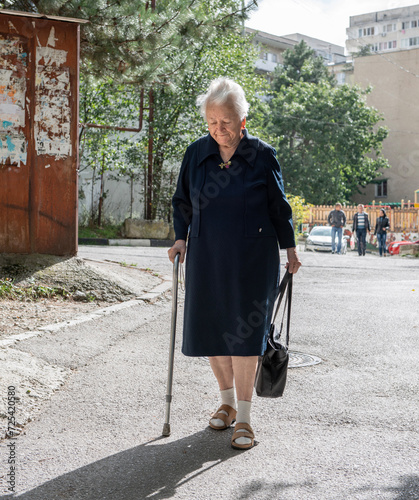 Yalta, Crimea - September 22, 2013: Old woman with a cane walking down street in sunny day