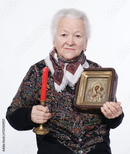 Portrait of old woman with icon posing in studio