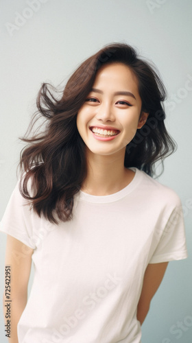 Young happy smiling Asian woman model wearing tshirt looking at camera on color background. Face skin hair care korean cosmetic and makeup, fashion ads. Beauty portrait. White t-shirt mock up template