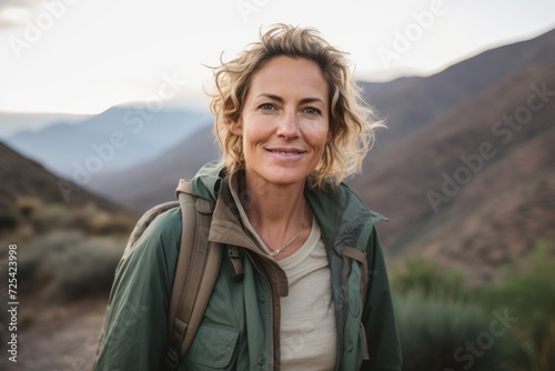 Portrait of a smiling woman with backpack looking at camera in the desert © Nerea