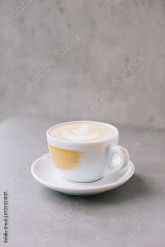Close-up of a cup of latte or cocoa on a gray stone background.