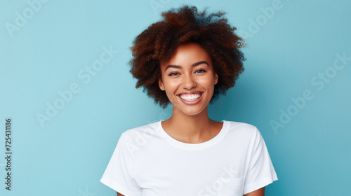 Young happy smiling African American woman model wearing tshirt standing on color background. Face skin hair care cosmetics makeup, fashion ads. Beauty portrait. White t-shirt mock up template .