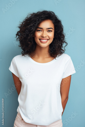 Young happy smiling Indian woman model wearing tshirt looking at camera standing on color background. Face skin care cosmetics makeup  fashion ads. Beauty portrait. White t-shirt mock up template .