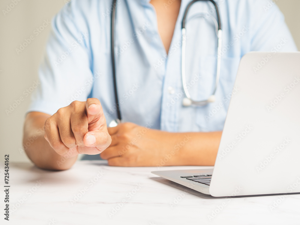 Doctor points on air while sitting at the desk in the hospital.