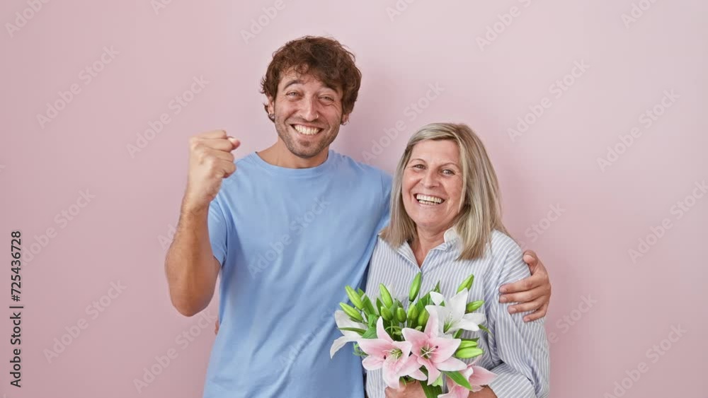 Excited mother and son, bouquet of flowers in hand, screaming in triumph! proud winners celebrate their victory over isolated pink background.
