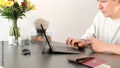 Pleased man typing on his laptop and purchasing travel tickets online