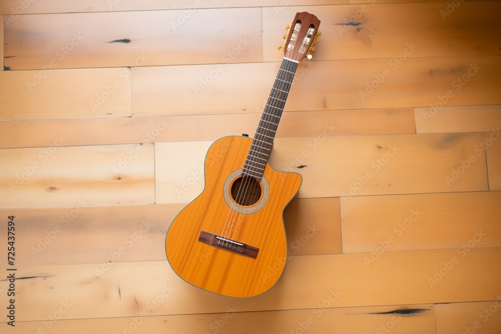 Fototapeta premium overhead shot of acoustic guitar on wooden floor