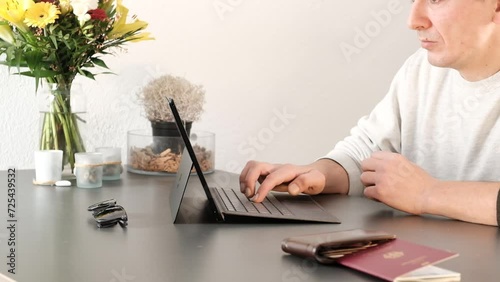 Pleased man typing on his laptop and purchasing travel tickets online