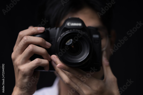 photographer take pictures Snapshot with camera. man hand holding with camera looking through lens.Concept for photographing articles Professionally.. © chathuporn
