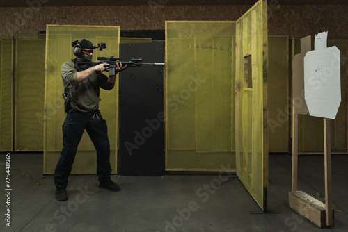 A man engages cqb tactical rifle shooting at a shooting range. photo