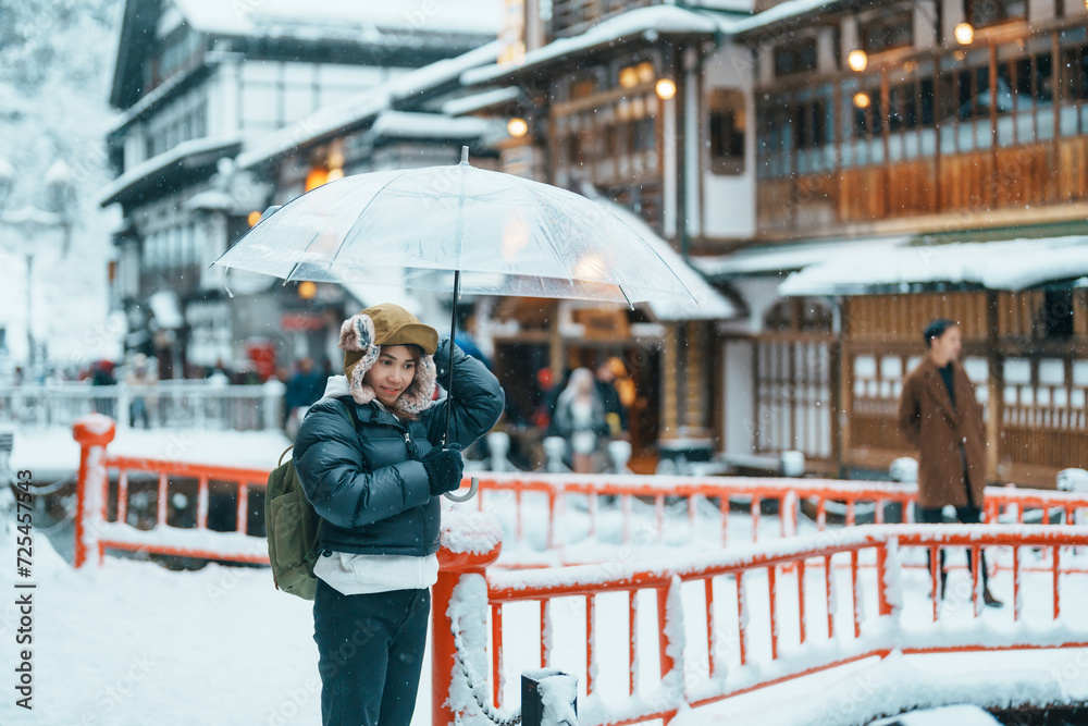 Woman tourist Visiting Ginzan Onsen in Yamagata, happy Traveler sightseeing Japanese Onsen village with Snow in winter season. landmark and popular for attraction in Japan. Travel and Vacation concept